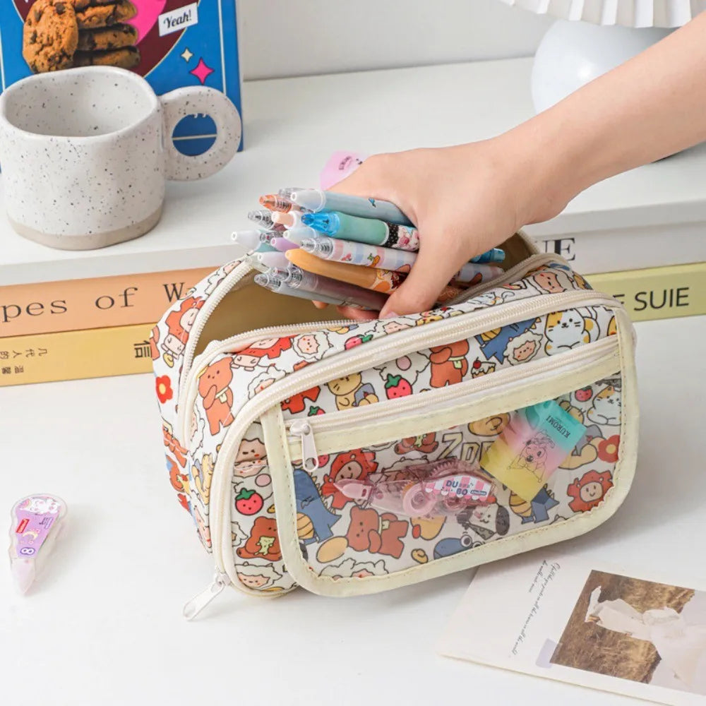 Pencil case with kawaii cartoon design held by a hand, surrounded by books and a mug on a table.