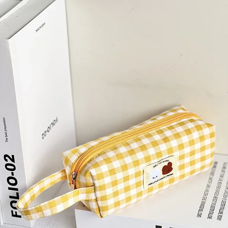 Yellow and white checkered kawaii pencil case with a small patch on a white surface