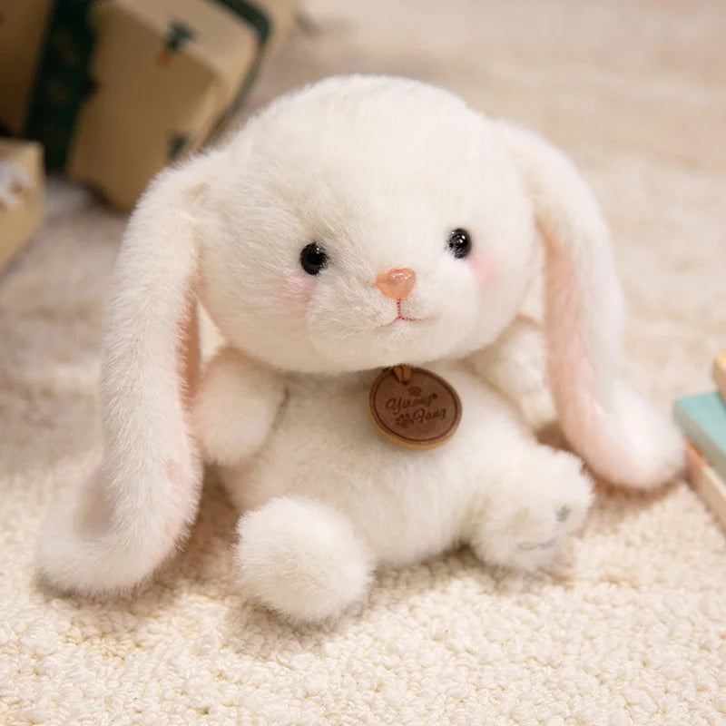 White plush bunny kawaii toy with a brown tag on a beige carpet
