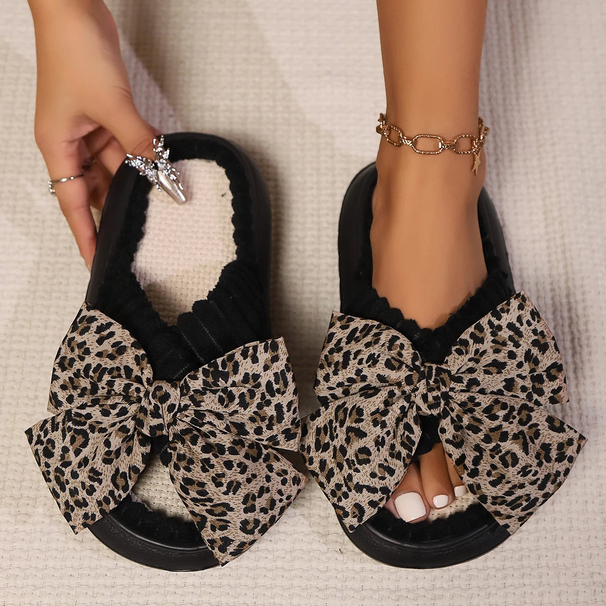Leopard print kawaii slippers with large bows worn by a person on a neutral background