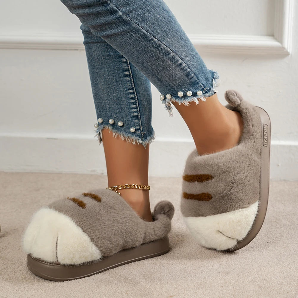 Person wearing gray kawaii fuzzy slippers with a cat design on a neutral background