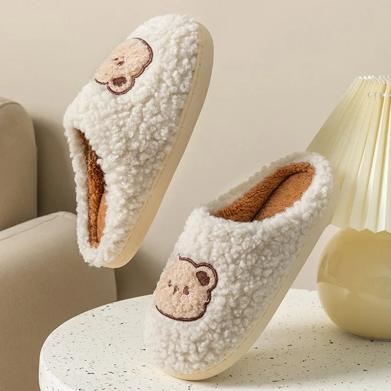 Pair of fluffy slippers with kawaii bear embroidery on a light background