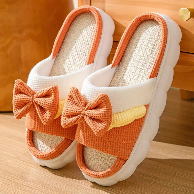 White slippers with kawaii orange bows on a wooden floor