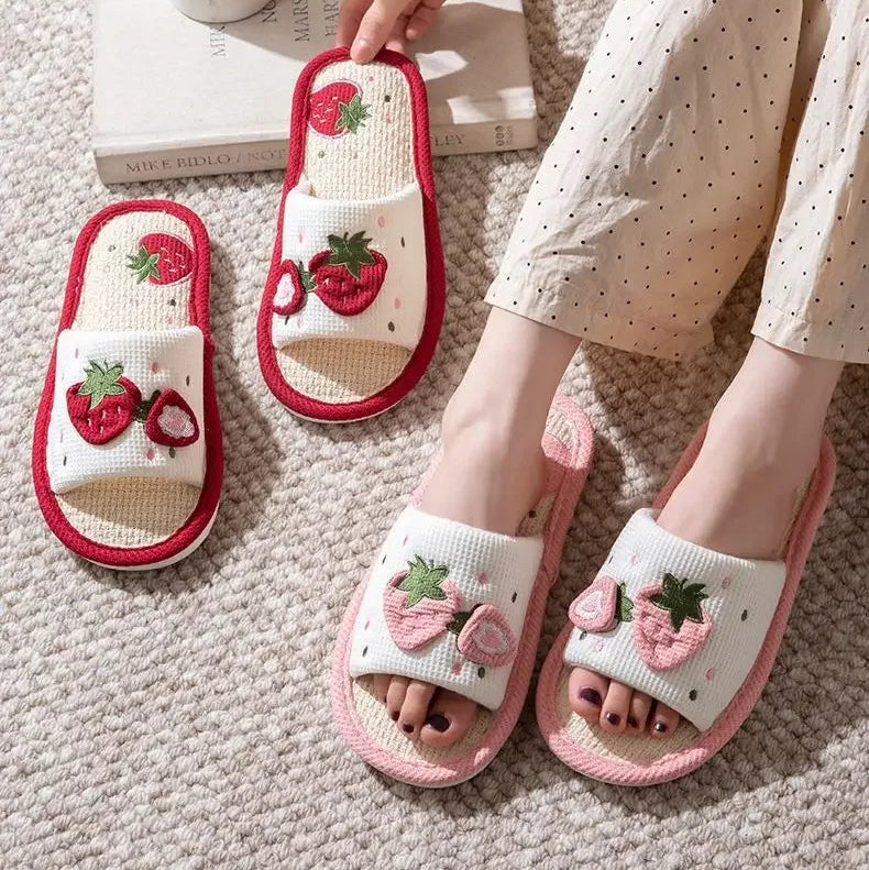 White slippers with kawaii strawberry design worn by a person on a carpeted floor.