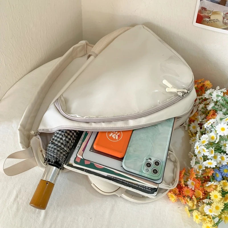Beige Kawaii backpack with items like a phone, book, and pen on a white surface with flowers in the background