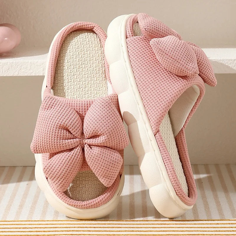 Pink kawaii slippers with a bow on a striped surface