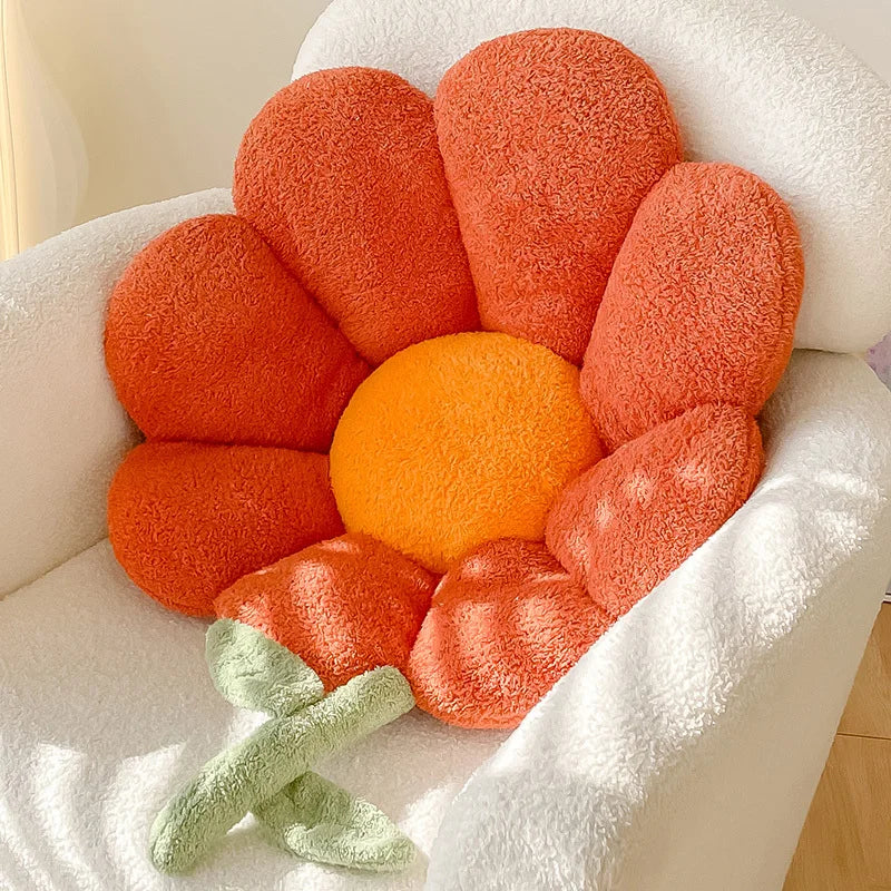 Kawaii flower-shaped cushion with orange center and red petals on a white couch.