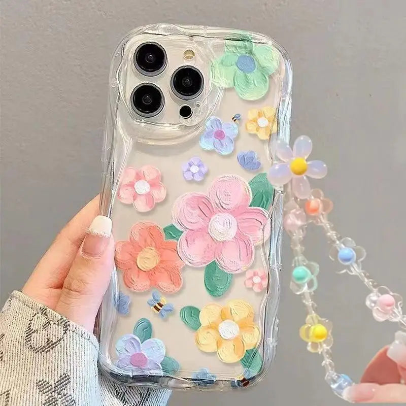 Phone case with colorful kawaii flowers and a lanyard held by a hand against a gray background