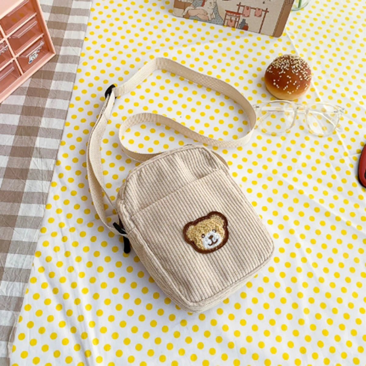 Beige knitted bag with Kawaii bear face design on a yellow polka dot tablecloth.