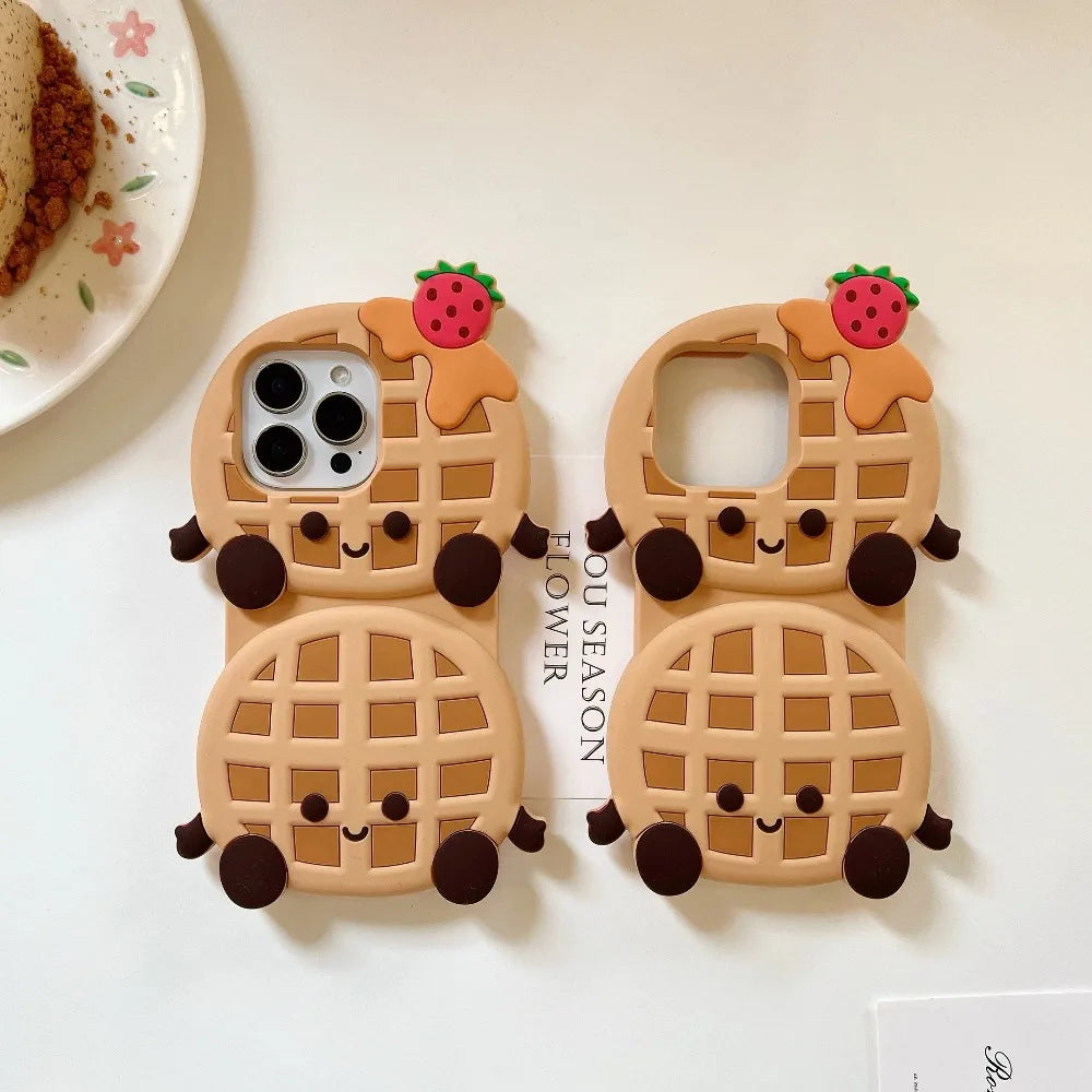 Two kawaii cartoon waffle phone cases on a white surface with a plate in the background.