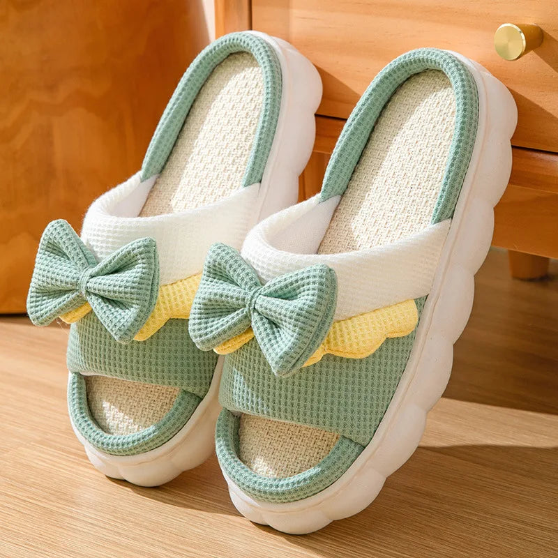 Pair of green kawaii slippers with bows on a wooden floor
