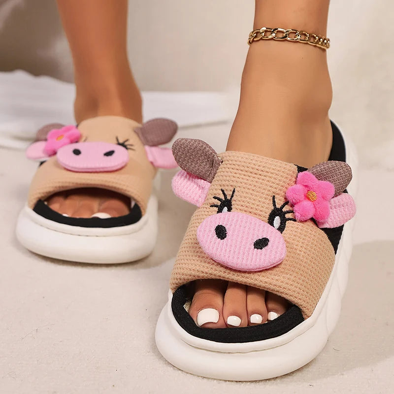 Kawaii cow-themed sandals with pink faces and flowers on a neutral background