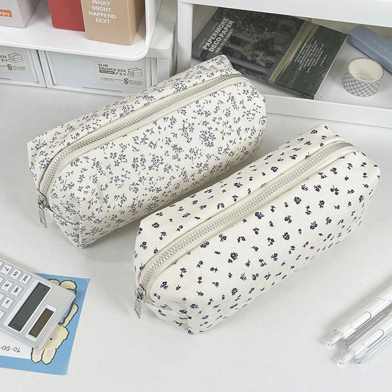 Two floral-patterned kawaii pencil cases on a desk with stationery items.