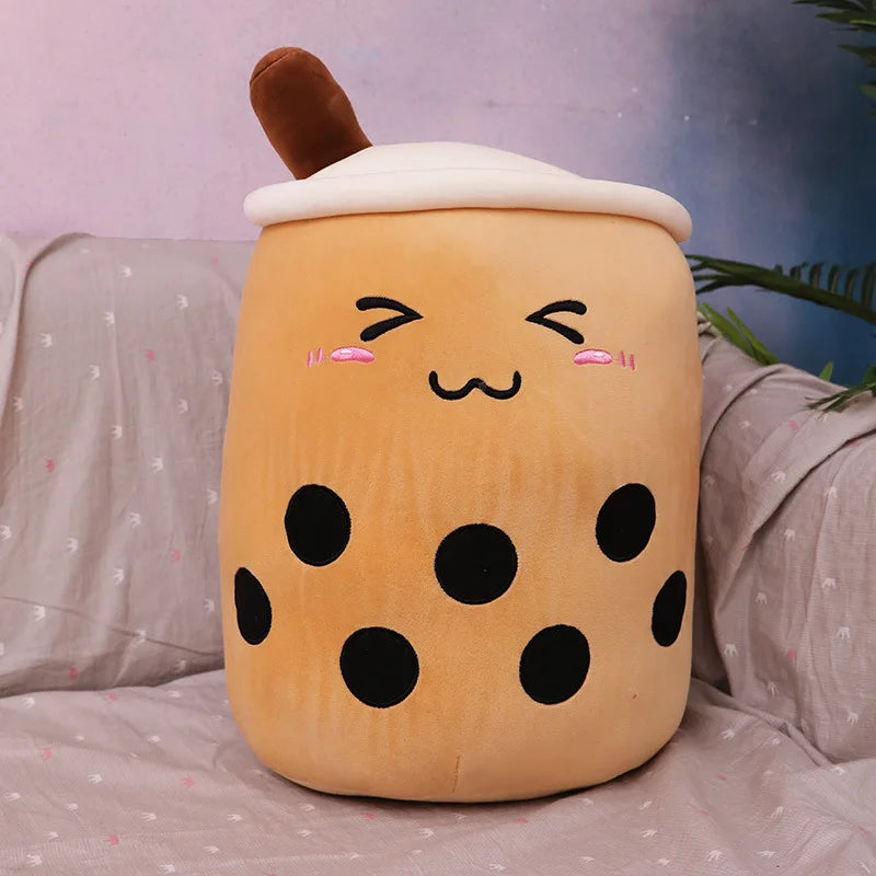 Plush kawaii toy shaped like a bubble tea cup with a face on a bed