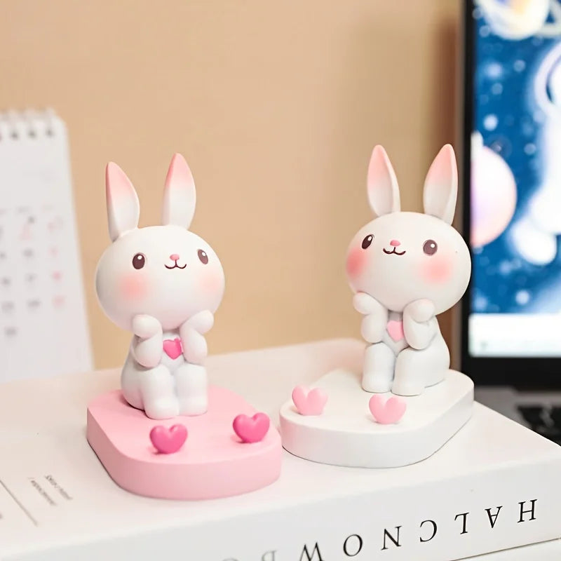 Two cute kawaii rabbit figurines with pink hearts on a desk.