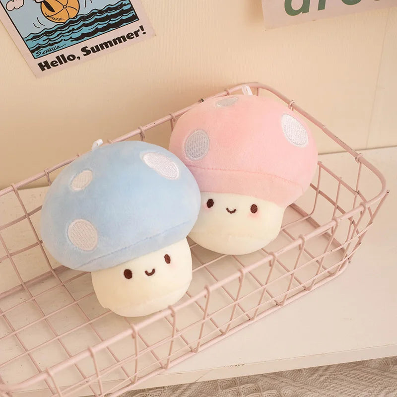 Two cute plush mushroom kawaii toys, one blue and one pink, on a wire basket.