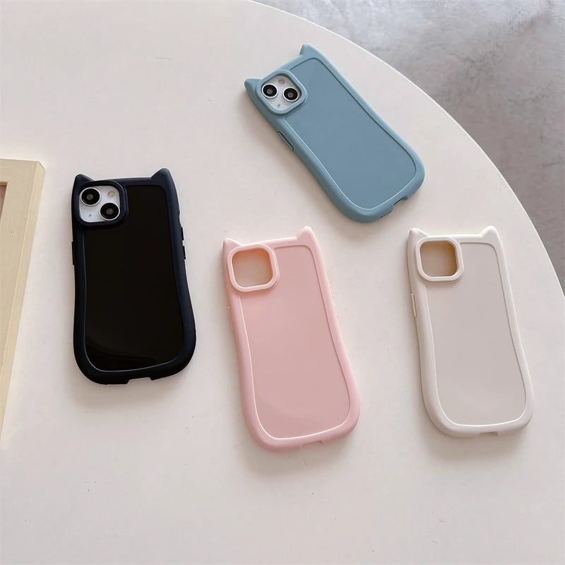 Four kawaii phone cases in black, blue, pink, and beige on a light surface.