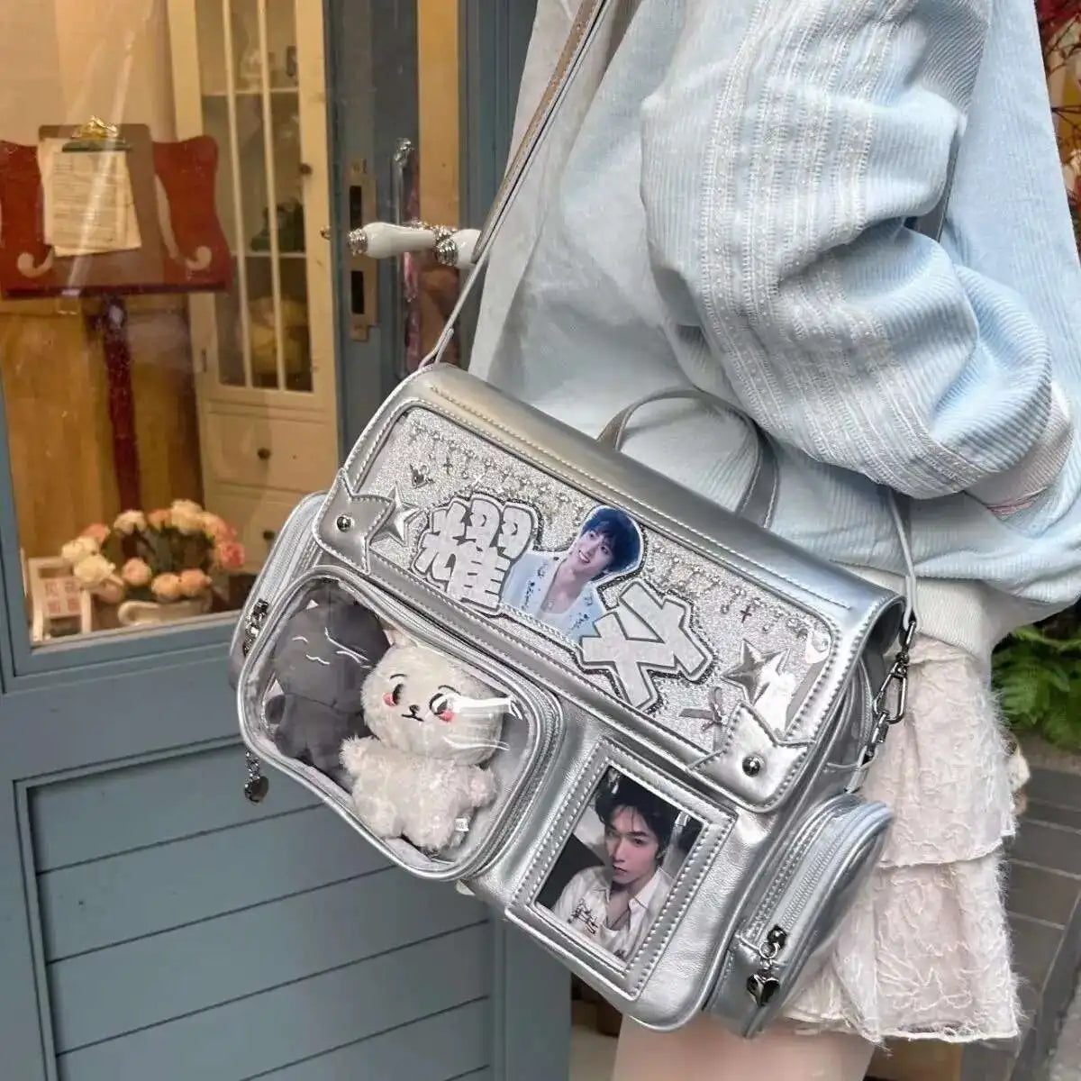 Silver Kawaii handbag with decorative elements and photos held by a person.