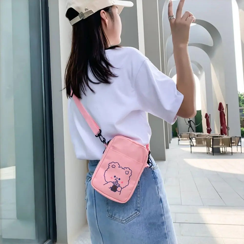 Person wearing a white shirt and pink crossbody bag with a Kawaii cartoon design, standing in an outdoor setting.