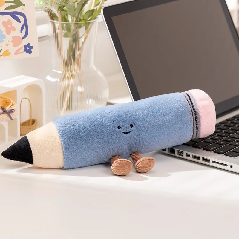 Kawaii plush pencil toy on a desk next to a laptop