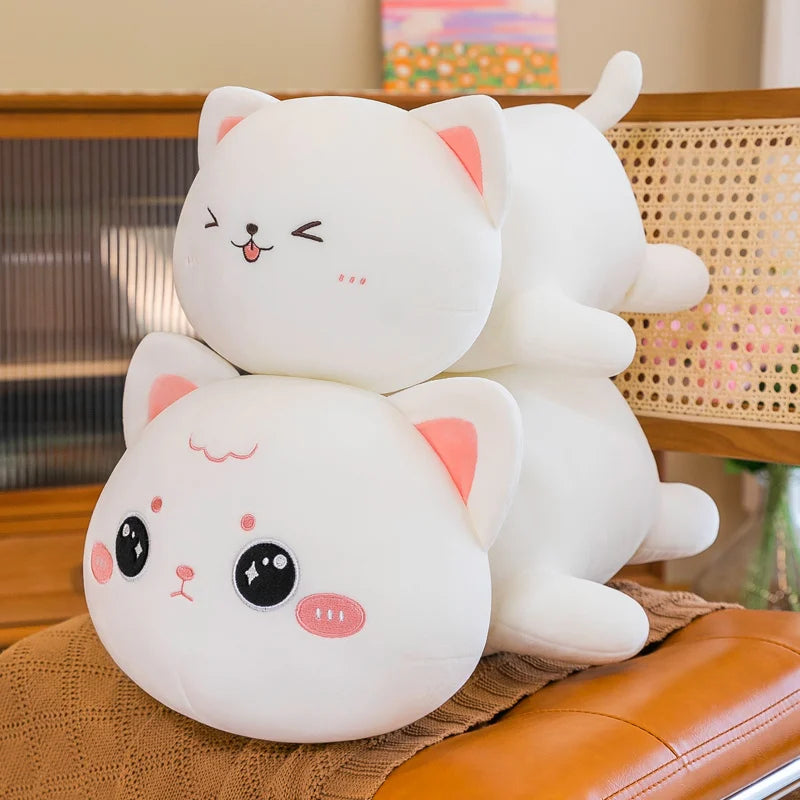Two cute kawaii plush cat toys stacked on top of each other on a chair.