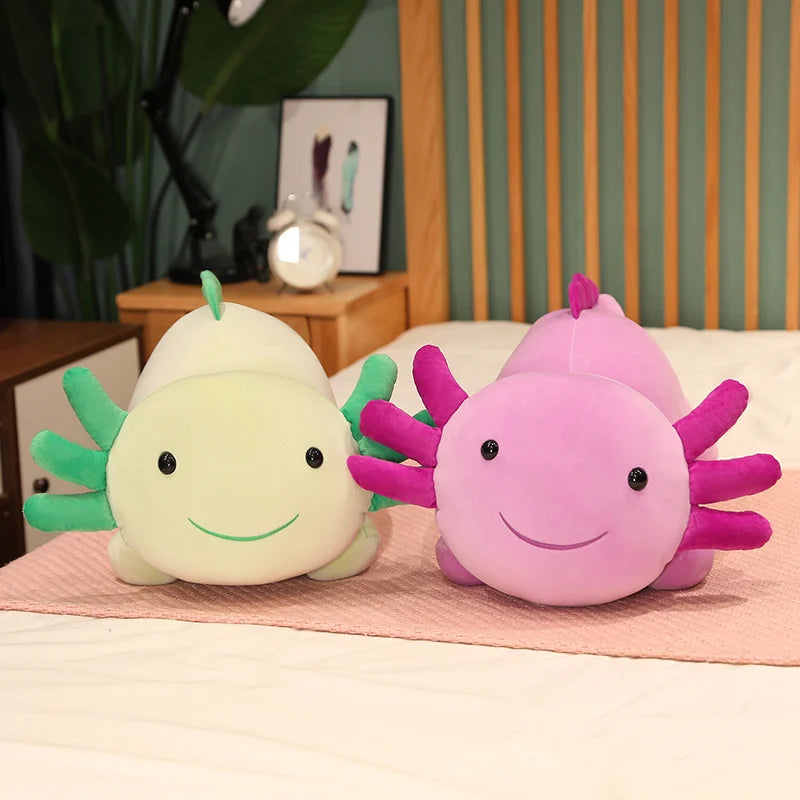 Two plush kawaii toys, one green and one pink, sitting on a bed with a striped headboard in the background.