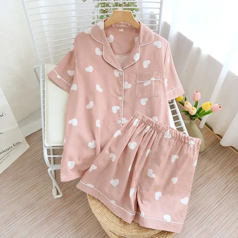 Pink pajama set with kawaii heart patterns on a wooden stool.