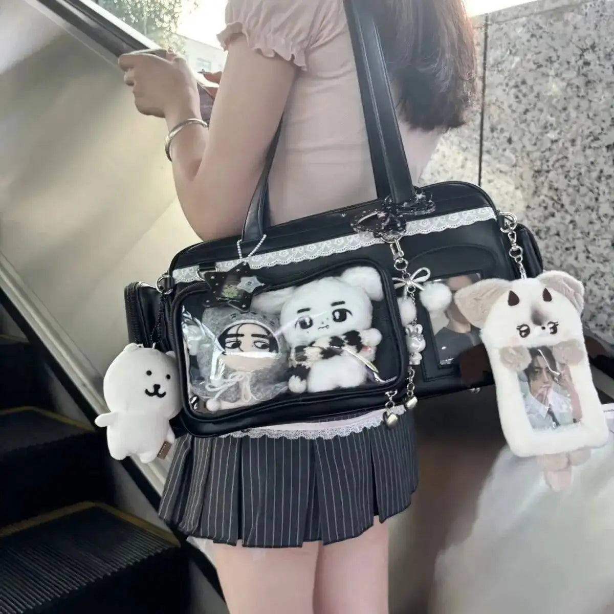 Person holding a black Kawaii handbag with cartoon character keychains, sitting on stairs.