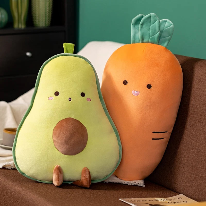 Kawaii plush avocado and carrot toys on a brown surface with a green wall in the background.