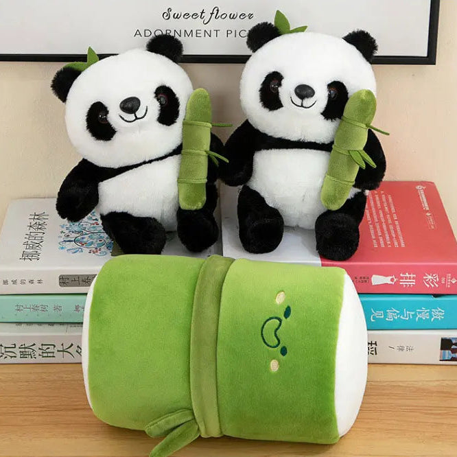 Two kawaii plush panda toys with a green bamboo leaf and a green pillow on books.