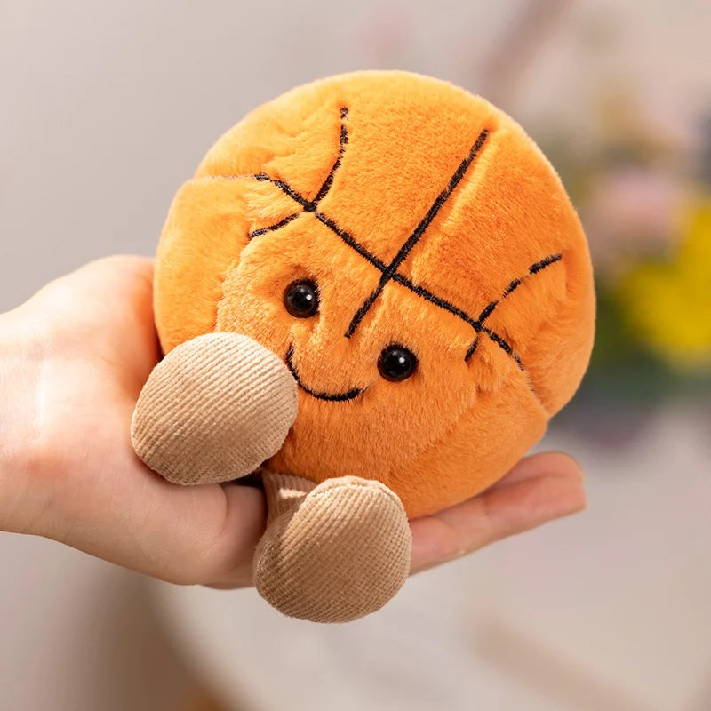 Plush kawaii toy basketball with a smiling face held in a hand against a blurred background