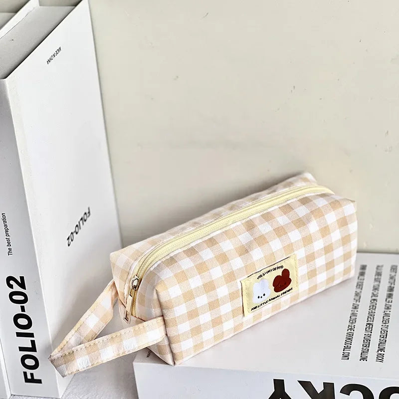 Beige checkered kawaii pouch with a cartoon label on a white surface