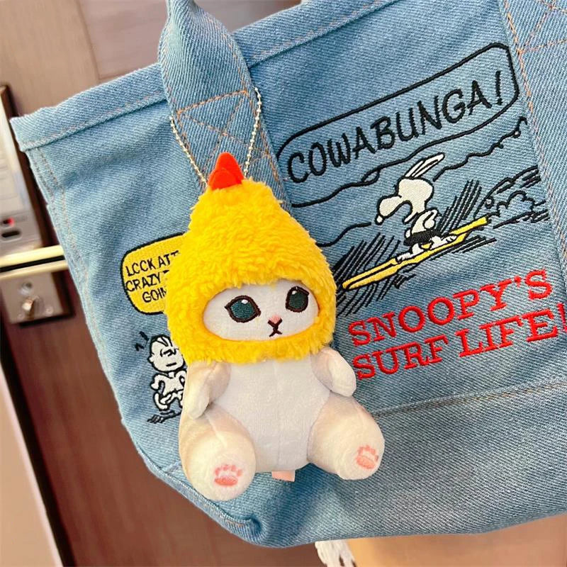 Plush kawaii toy with a yellow hood hanging from a denim bag with Snoopy designs.