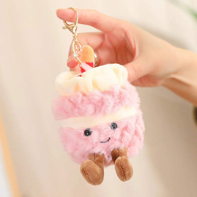 Plush keychain shaped like a pink cloud with a kawaii smiling face held by a hand against a neutral background