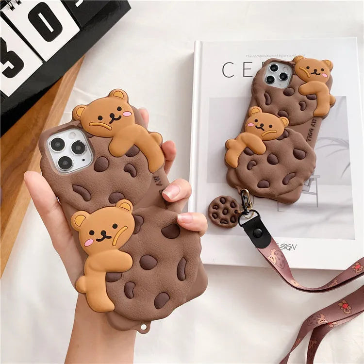 Phone case with kawaii bear design held by a hand, with another case and lanyard in the background.