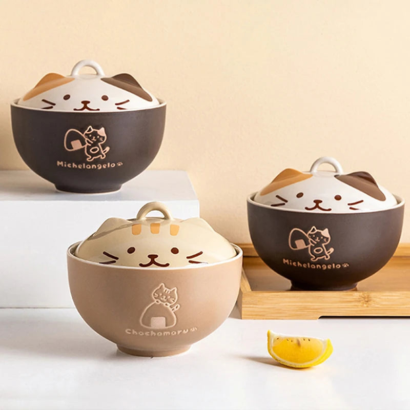 Three kawaii cartoon-style ceramic bowls with cat faces on a light beige background