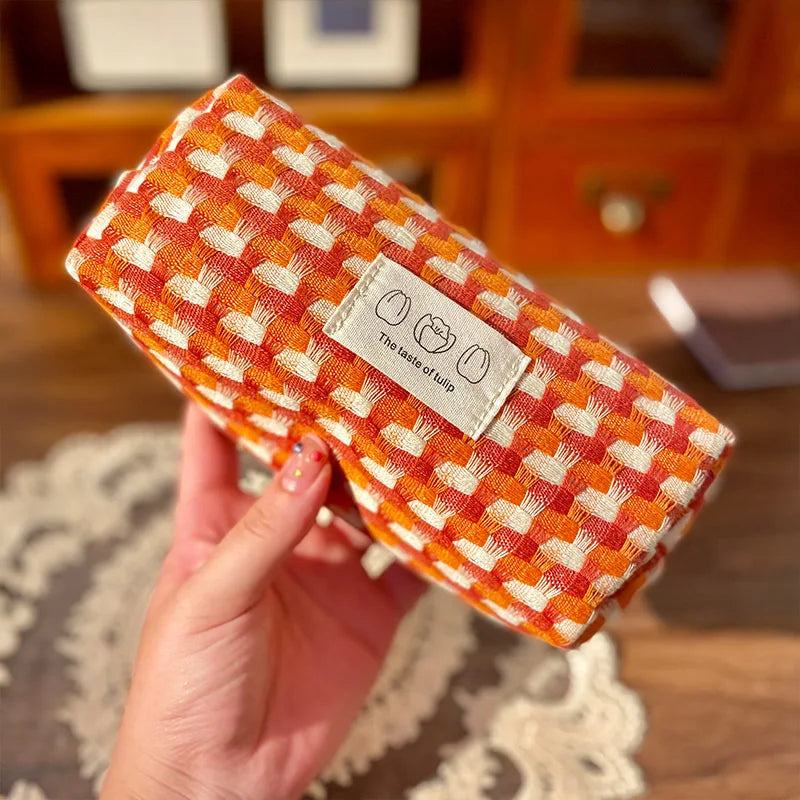 Orange and white checkered kawaii pouch held by a hand with a blurred background