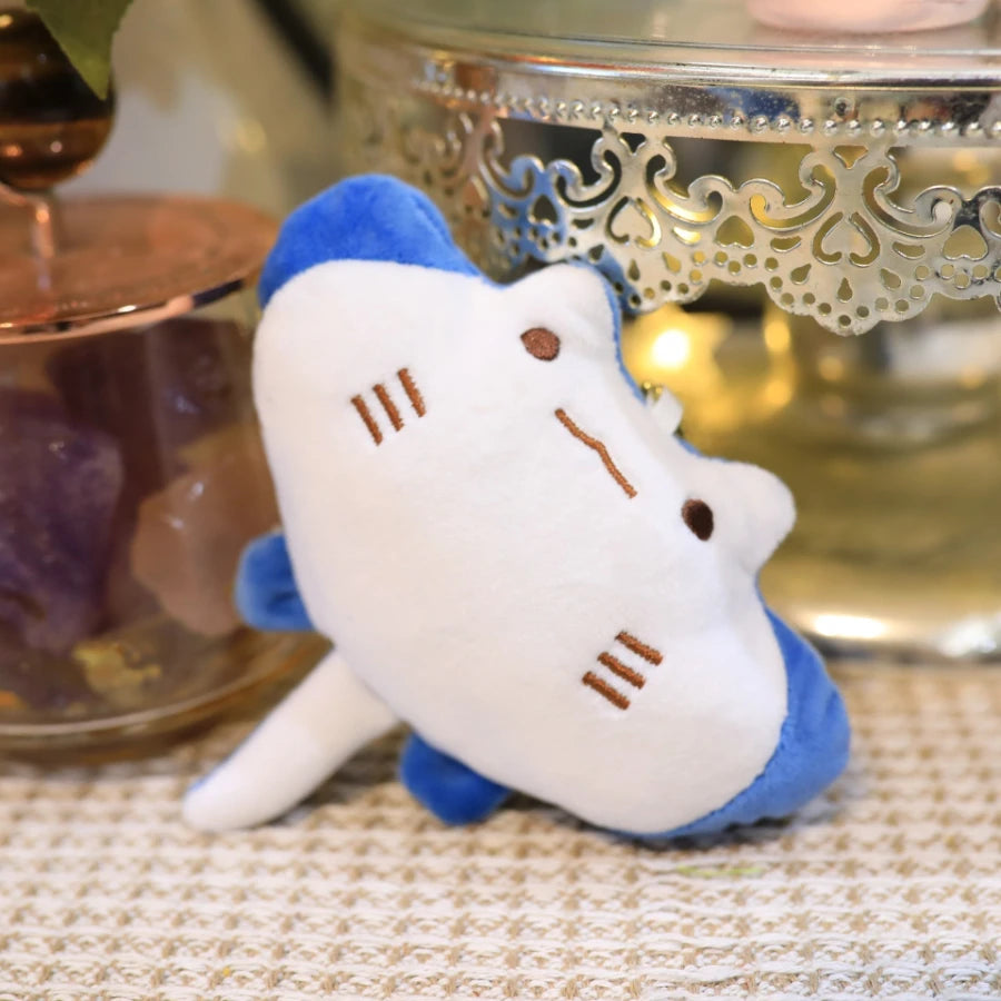 Plush kawaii toy shark with blue fins on a textured surface