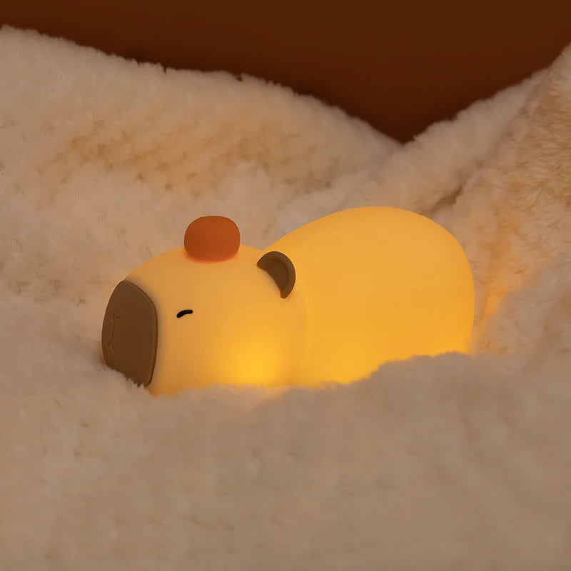 Cute kawaii capybara night light emitting a warm glow on a soft surface.