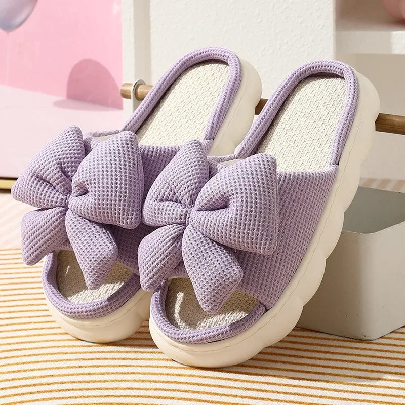 Purple slippers with large kawaii bows on a striped surface