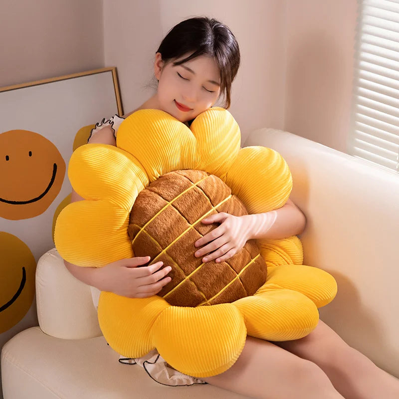 Person sitting on a couch holding a large yellow sunflower-shaped kawaii pillow.