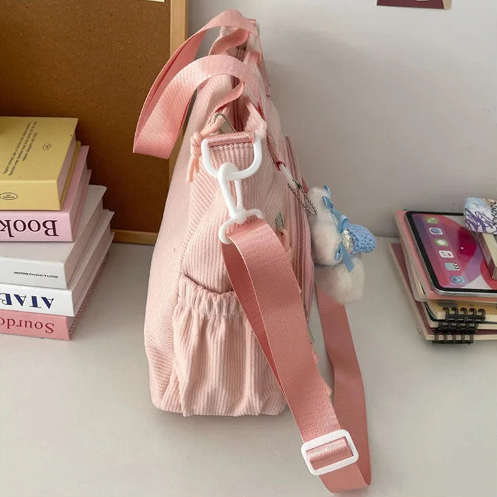 Pink Kawaii bag with a strap on a surface with books and a phone in the background