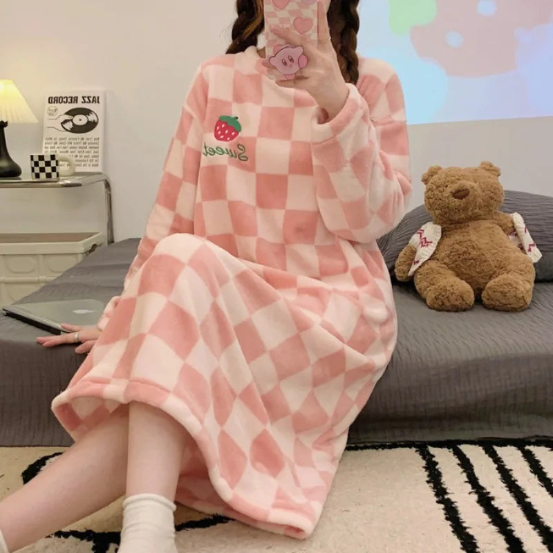 Person wearing a pink checkered kawaii robe with a strawberry design, sitting on a bed with a teddy bear.