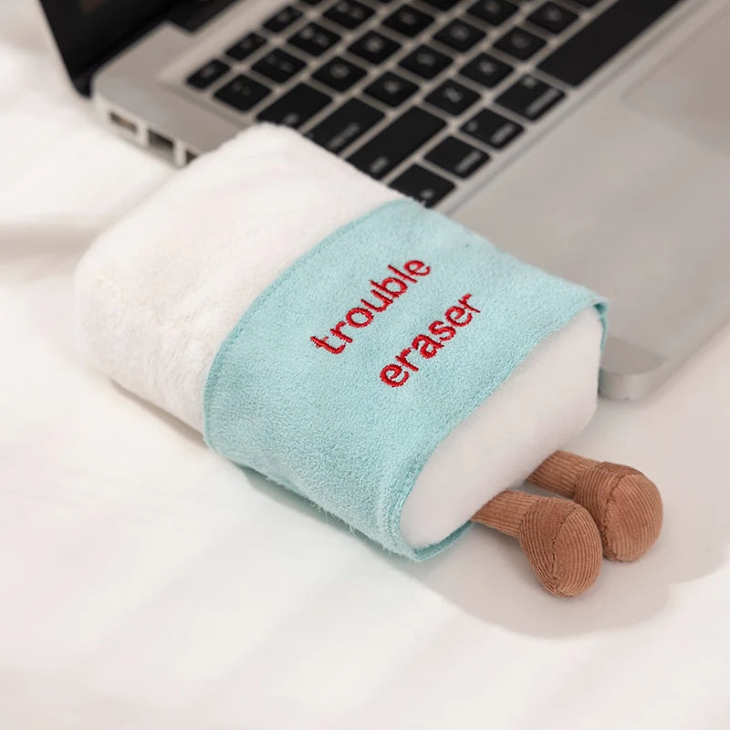 Kawaii plushy in the shape of an eraser on a laptop with a small dog toy.