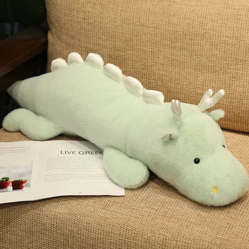 Plush dragon kawaii toy on a beige couch with a magazine underneath