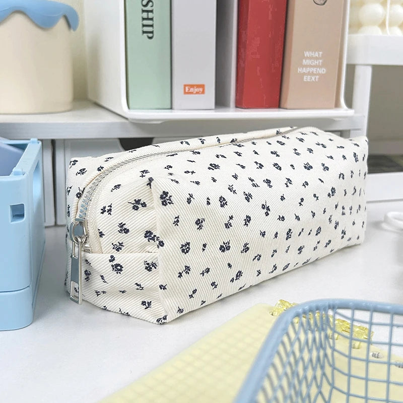 White floral-patterned kawaii pencil case on a desk with books in the background