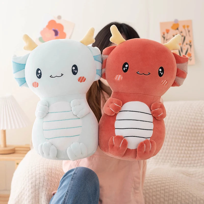 Two axolotl-shaped kawaii plush toys held by a person in a room.