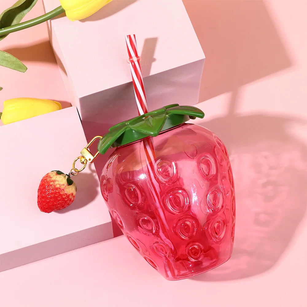 Kawaii strawberry-shaped tumbler with a straw on a pink background