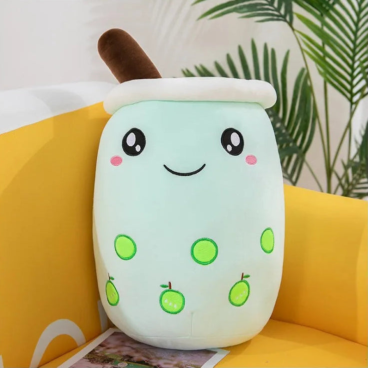 Cute kawaii plush toy resembling a bubble tea cup with a smiling face on a yellow couch.
