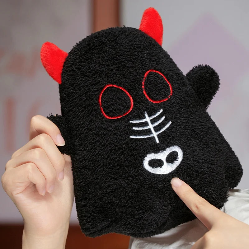 Black plush kawaii toy with red horns and white face details held by a person.